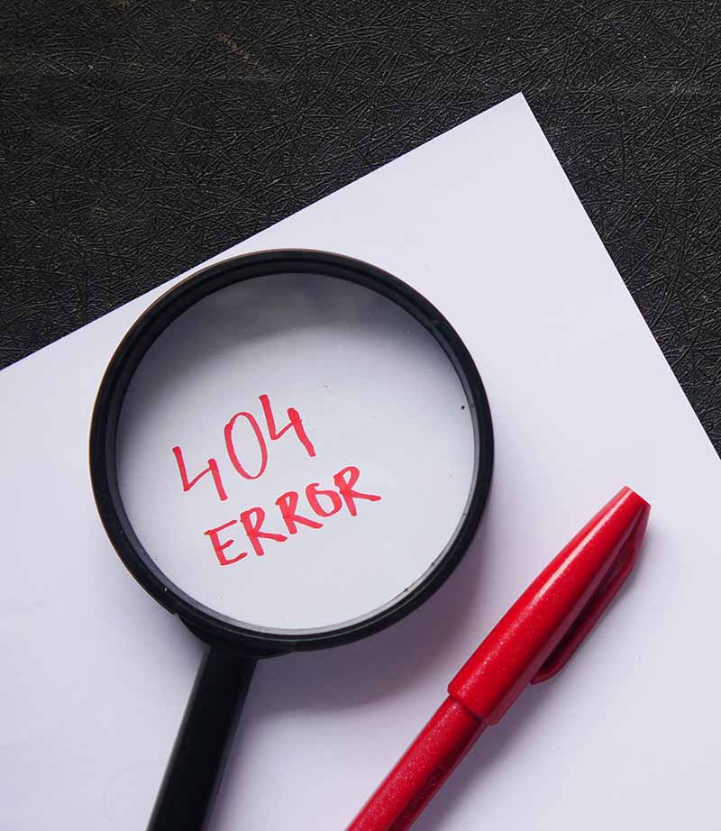 Error 404 image of a piece of paper, red marker, magnifying glass, and a "404 error" written on the paper. This is a decorative image.